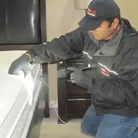Bed bug inspection technician checking a mattress and bed frame for signs of infestation in Columbus, OH