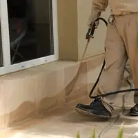 General pest control technician spraying exterior perimeter around a home in Columbus, OH