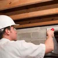 Termite inspection technician checking a basement wall and framing for termite activity in Columbus, OH