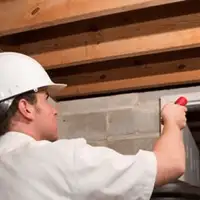 Termite inspection technician checking a basement wall and framing for termite activity in Columbus, OH